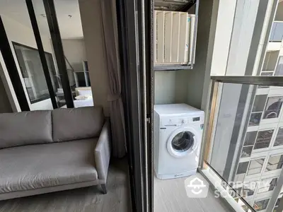 Modern apartment with a cozy living room seamlessly extending to a convenient balcony with a washing machine, offering urban living with practical amenities.