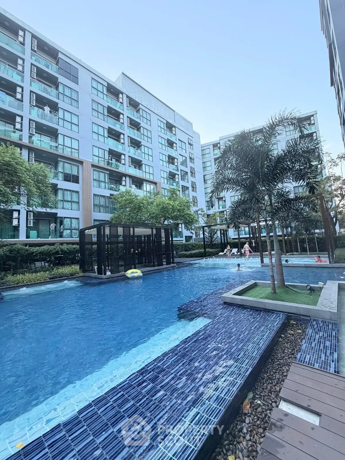 Modern condominium with luxurious pool and lush greenery, perfect for urban living.