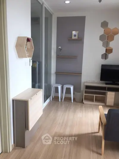 Modern living room with stylish decor and wooden flooring, featuring a TV and wall-mounted shelves.