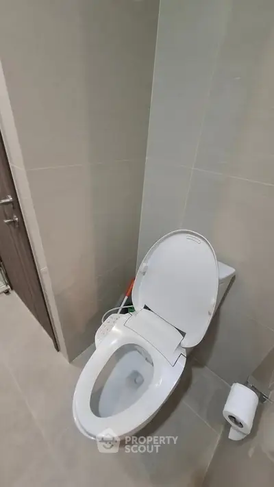 Modern bathroom with sleek toilet and neutral tiles, perfect for contemporary living.