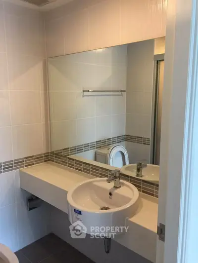 Modern bathroom with sleek sink and large mirror in a stylish apartment.