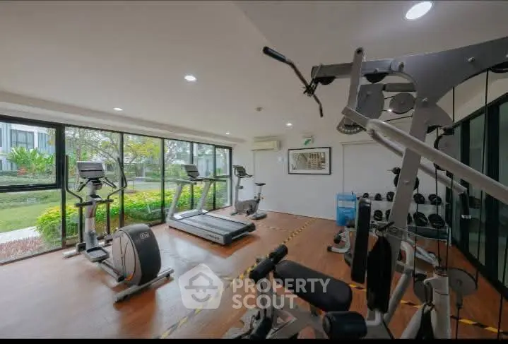Modern gym with large windows and fitness equipment in a residential building.