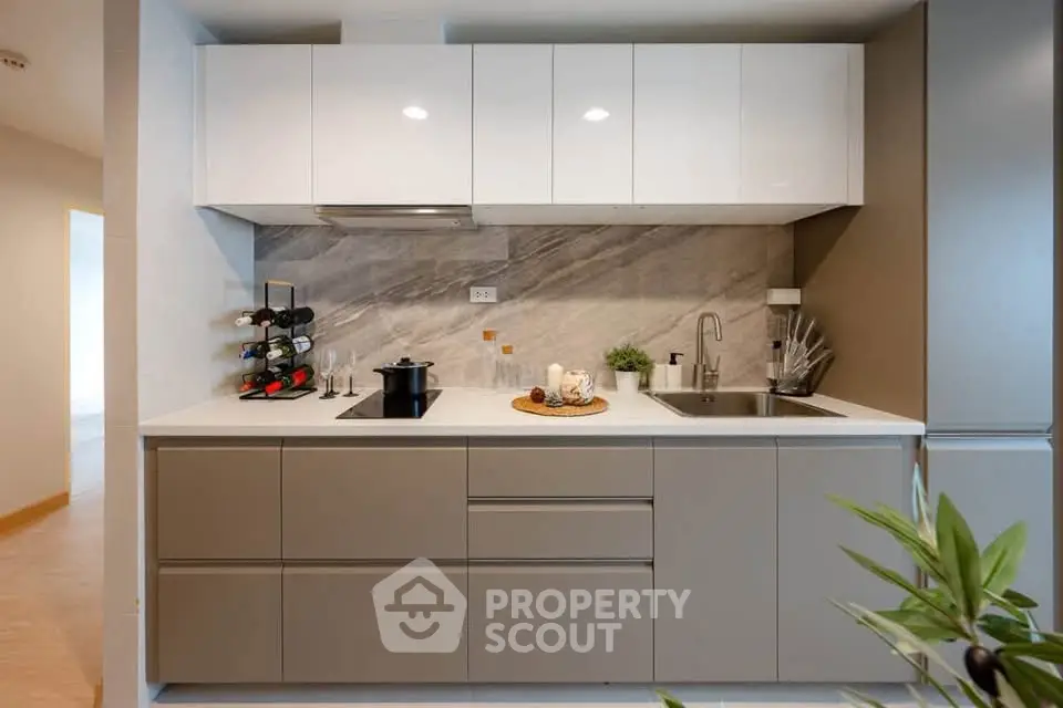 Modern kitchen with sleek cabinetry and marble backsplash, featuring a wine rack and stainless steel sink.