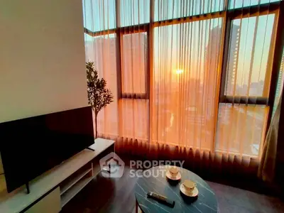 Stunning living room with floor-to-ceiling windows offering breathtaking city sunset views.