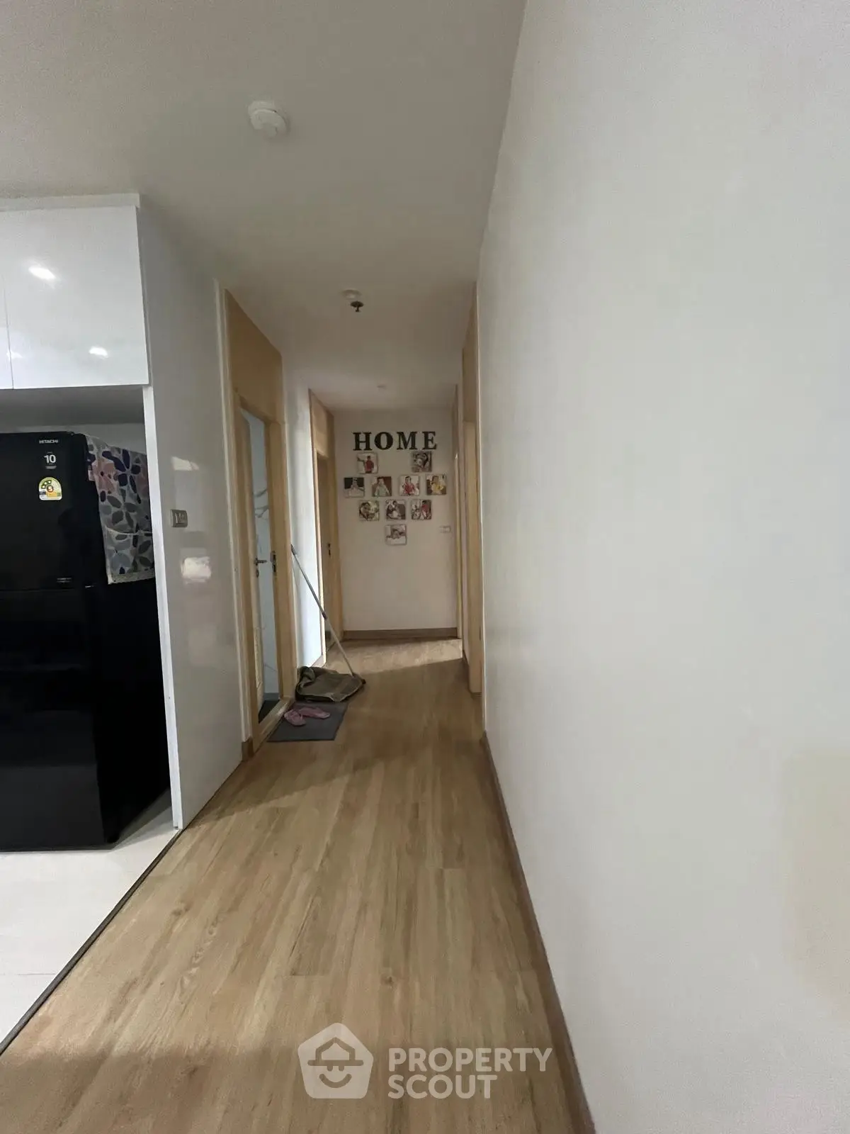 Spacious hallway with wooden flooring leading to cozy rooms, featuring modern decor and a welcoming atmosphere.