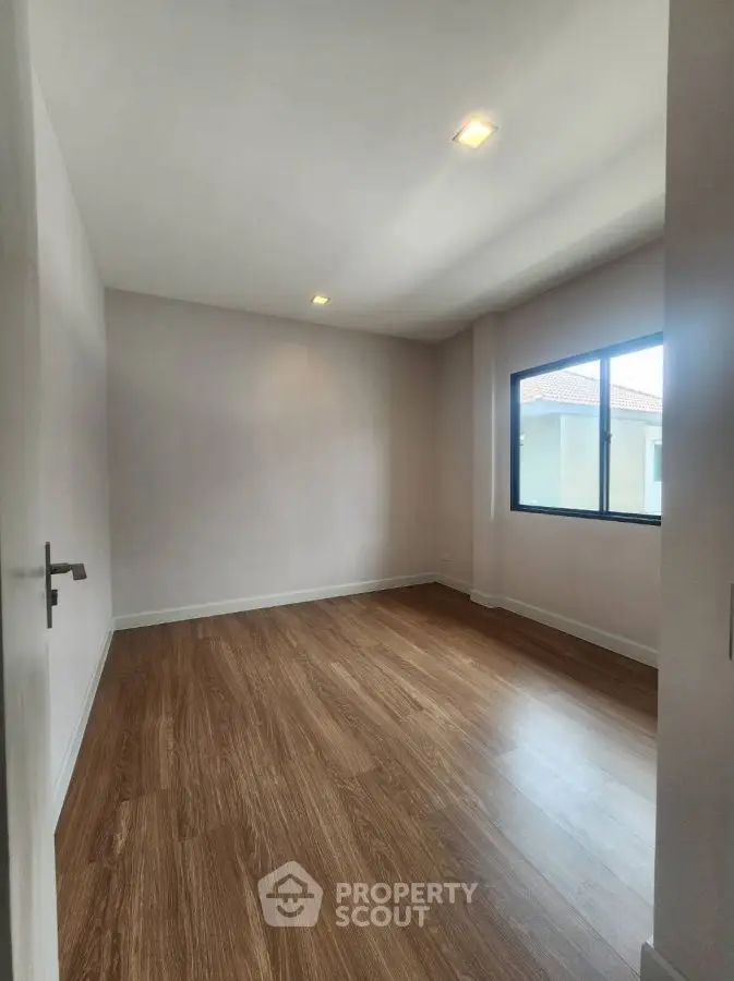 Spacious empty room with wooden flooring and large window
