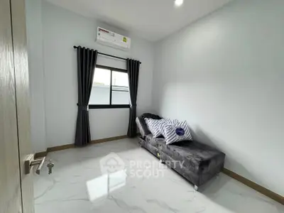 Modern minimalist bedroom with sleek gray sofa and air conditioning