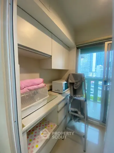 Compact storage room with city view, featuring modern cabinetry and a microwave.