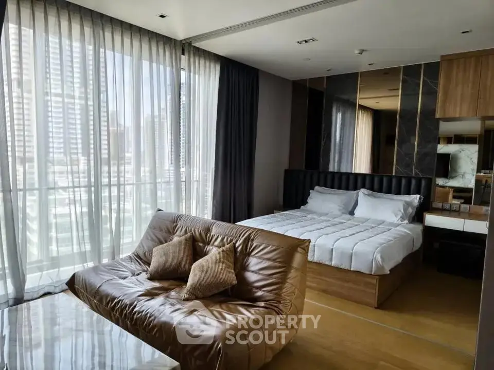 Luxurious bedroom with city view, featuring modern decor and cozy seating area.