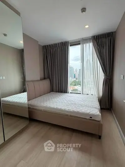 Modern bedroom with city view, featuring a large window and stylish decor in a high-rise apartment.