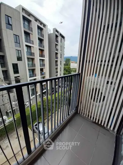 Modern apartment balcony with city view and nearby buildings.