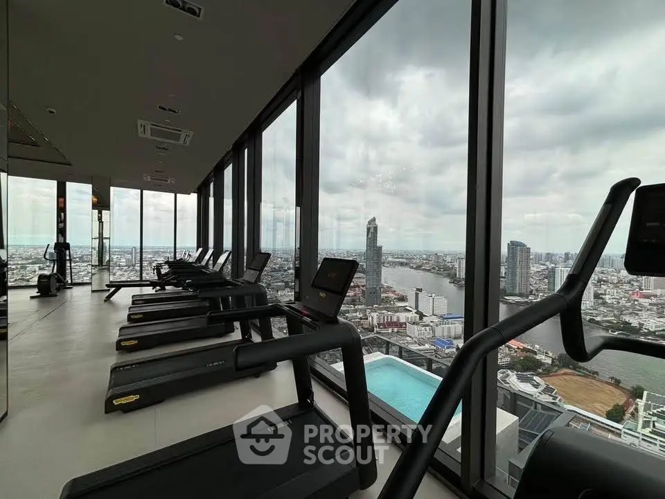 Luxurious high-rise gym with panoramic city and river views, featuring state-of-the-art equipment.