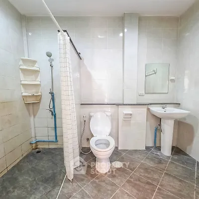 Spacious bathroom with modern fixtures and tiled flooring, featuring a shower and toilet.