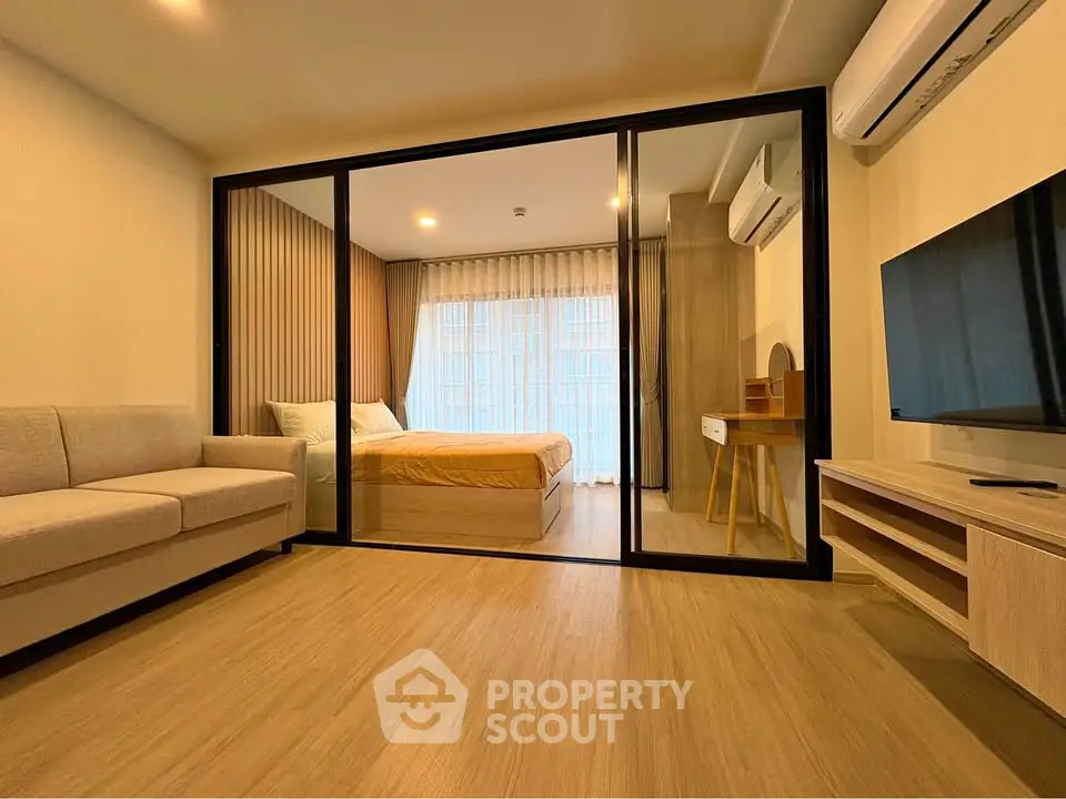 Modern apartment interior with glass partition, cozy living room, and stylish bedroom.