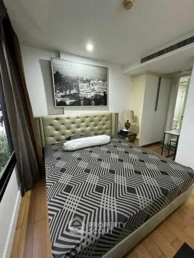 Modern bedroom with stylish decor and large window in a cozy apartment.