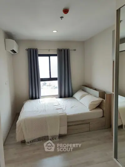 Cozy bedroom with modern decor and large window offering natural light