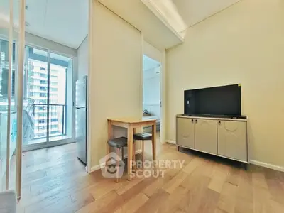 Modern apartment interior with wooden flooring, small dining area, and balcony view.