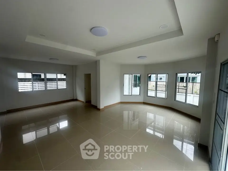 Spacious unfurnished living room with large windows and glossy tiled floors