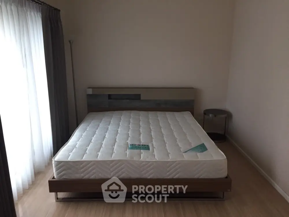 Spacious and well-lit bedroom with a large bed, hardwood flooring, and elegant curtains, perfect for a restful retreat in a modern home.