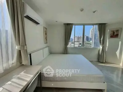 Bright and spacious bedroom with city view, featuring large windows and modern furnishings.