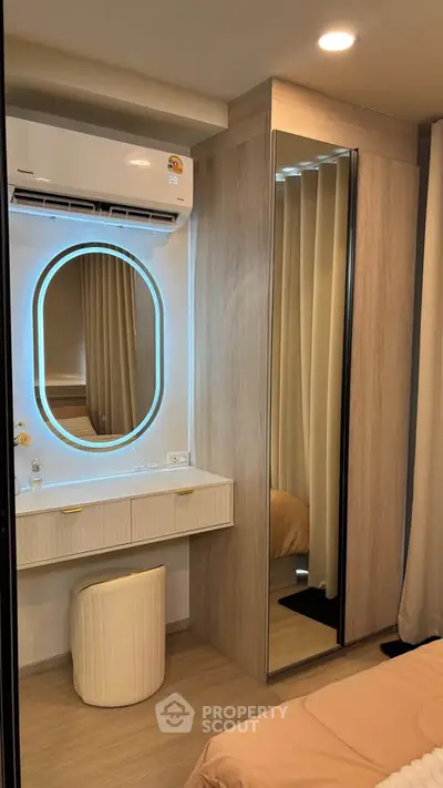 Modern bedroom with stylish vanity and mirrored wardrobe, featuring elegant lighting and cozy decor.