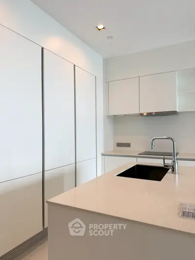 Modern minimalist kitchen with sleek white cabinets and island sink.