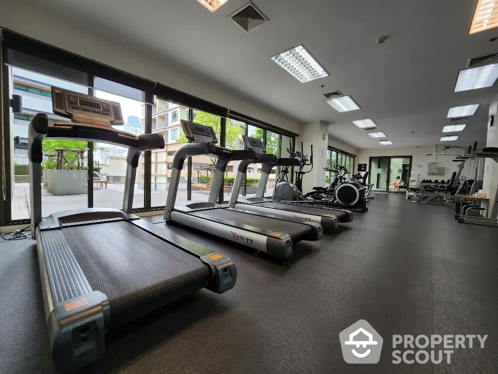 Spacious modern gym with state-of-the-art equipment and large windows offering a bright and airy atmosphere.