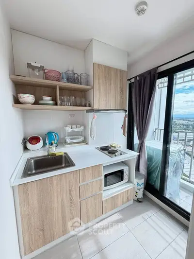 Modern compact kitchen with balcony view, featuring wooden cabinets and sleek appliances.