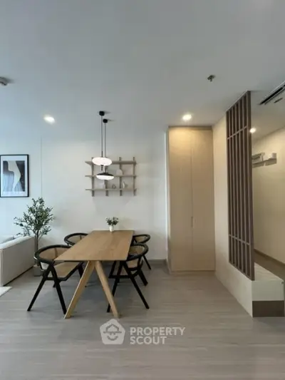 Modern dining area with wooden table and stylish chairs in open-plan living space.