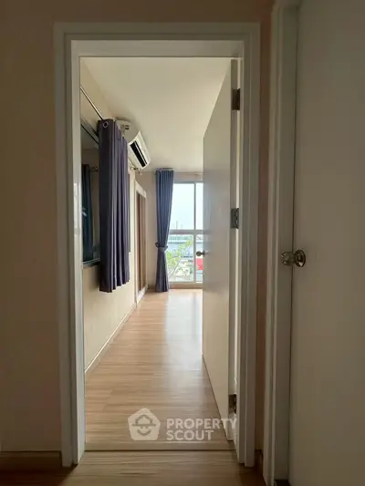 Bright bedroom with wooden flooring and large window offering natural light and city view.