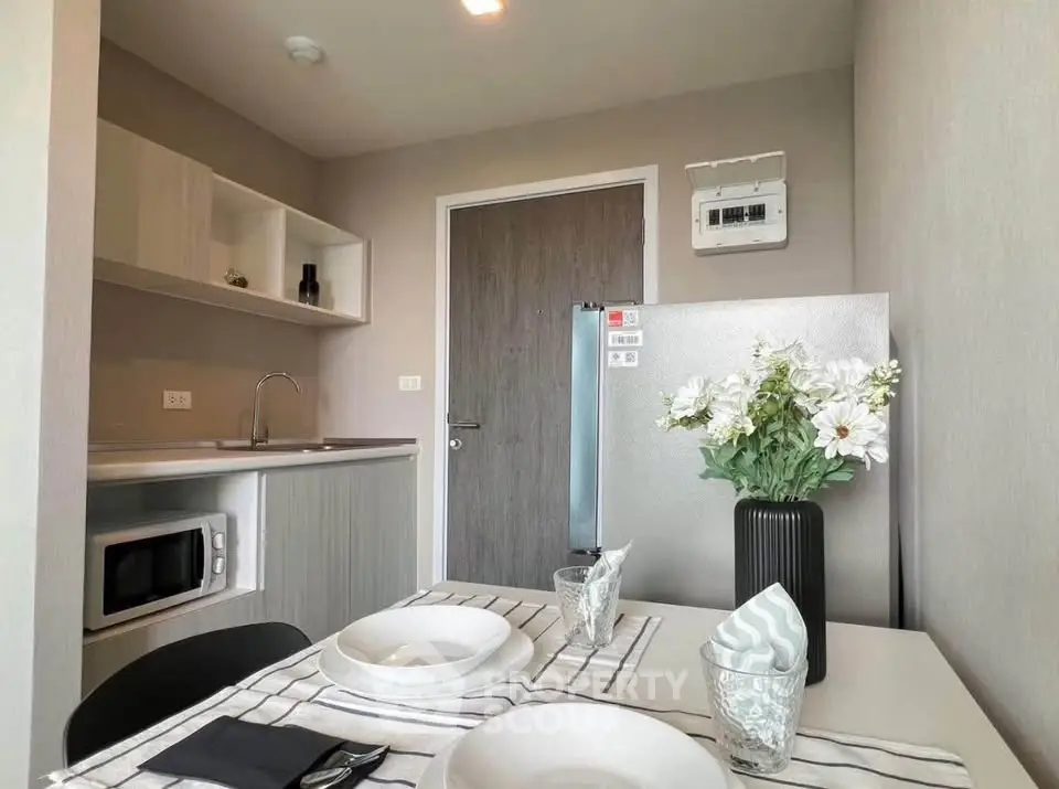 Modern kitchen with sleek design, featuring a dining table set for two, microwave, and stylish decor.