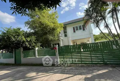 Charming two-story house with lush greenery and a modern green fence, perfect for family living.