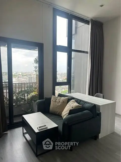 Modern living room with large windows and balcony view in urban apartment.