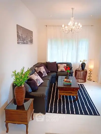 Elegant living room with chandelier, cozy sofa, and stylish decor in a bright, inviting space.