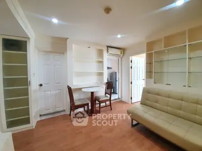 Spacious and well-lit living room with sleek hardwood flooring, comfortable beige sofa, and a cozy dining area, perfect for entertaining guests or relaxing at home.