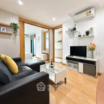 Modern living room with sleek furniture and wooden flooring, featuring a cozy ambiance and stylish decor.