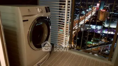 High-rise balcony with washing machine and stunning city view at night.