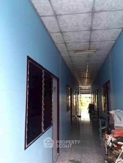 Narrow corridor with blue walls and tiled floor in residential building.