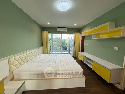 Spacious bedroom with modern design and balcony access, featuring stylish green and yellow accents.