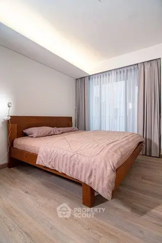 Modern bedroom with wooden flooring and large window for natural light
