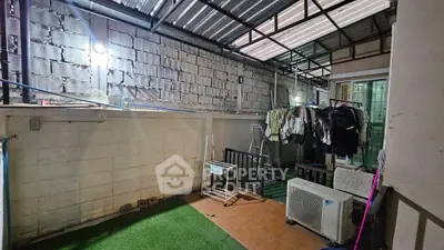 Covered outdoor area with laundry setup and artificial grass flooring.
