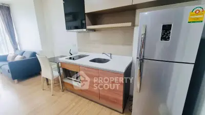 Modern kitchen with sleek appliances and cozy living area in open layout apartment.