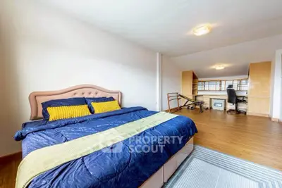 Spacious bedroom with modern decor and study area, featuring wooden flooring and ample natural light.