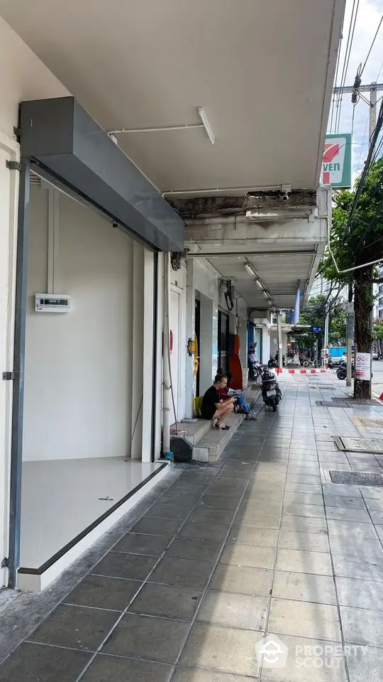 Street view of commercial property with sidewalk and storefronts in urban area.