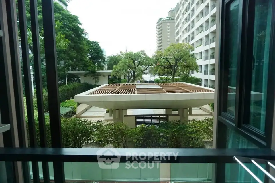 Stunning view from a modern apartment balcony overlooking lush greenery and a stylish building facade.
