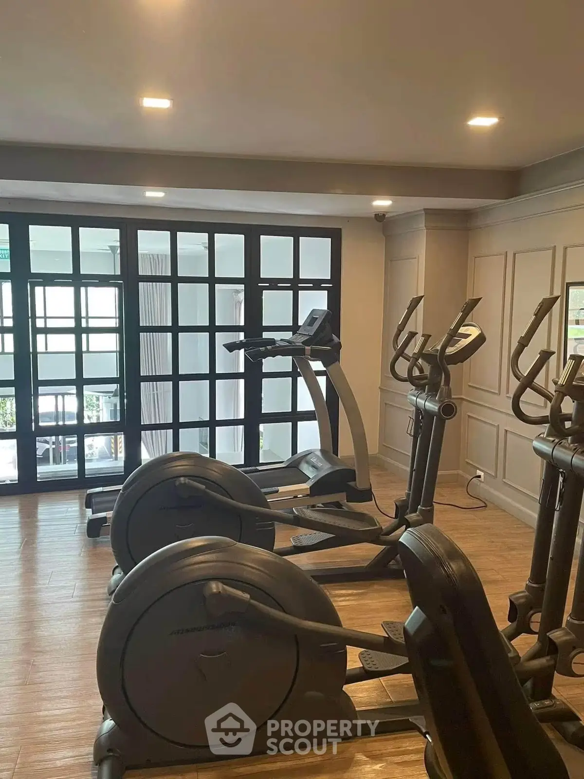 Modern gym with exercise equipment and large windows in a residential building.