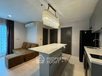Modern living room with elegant chandelier and open kitchen layout in a stylish apartment.