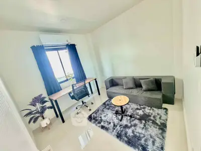 Modern living room with sleek sofa, stylish desk, and large window for natural light.