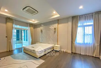 Spacious modern bedroom with large windows and elegant decor, featuring a comfortable bed and stylish lighting.