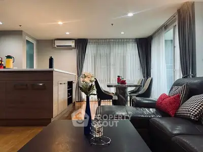 Modern living room with open kitchen, stylish decor, and ample natural light.
